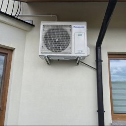 Cleanline Energy Sp. z o.o. - Biała klimatyzacja Panasonic zamontowana na elewacji domu, widoczny numer budynku 362a, obok okno w brązowej ramie i czarna rynna.