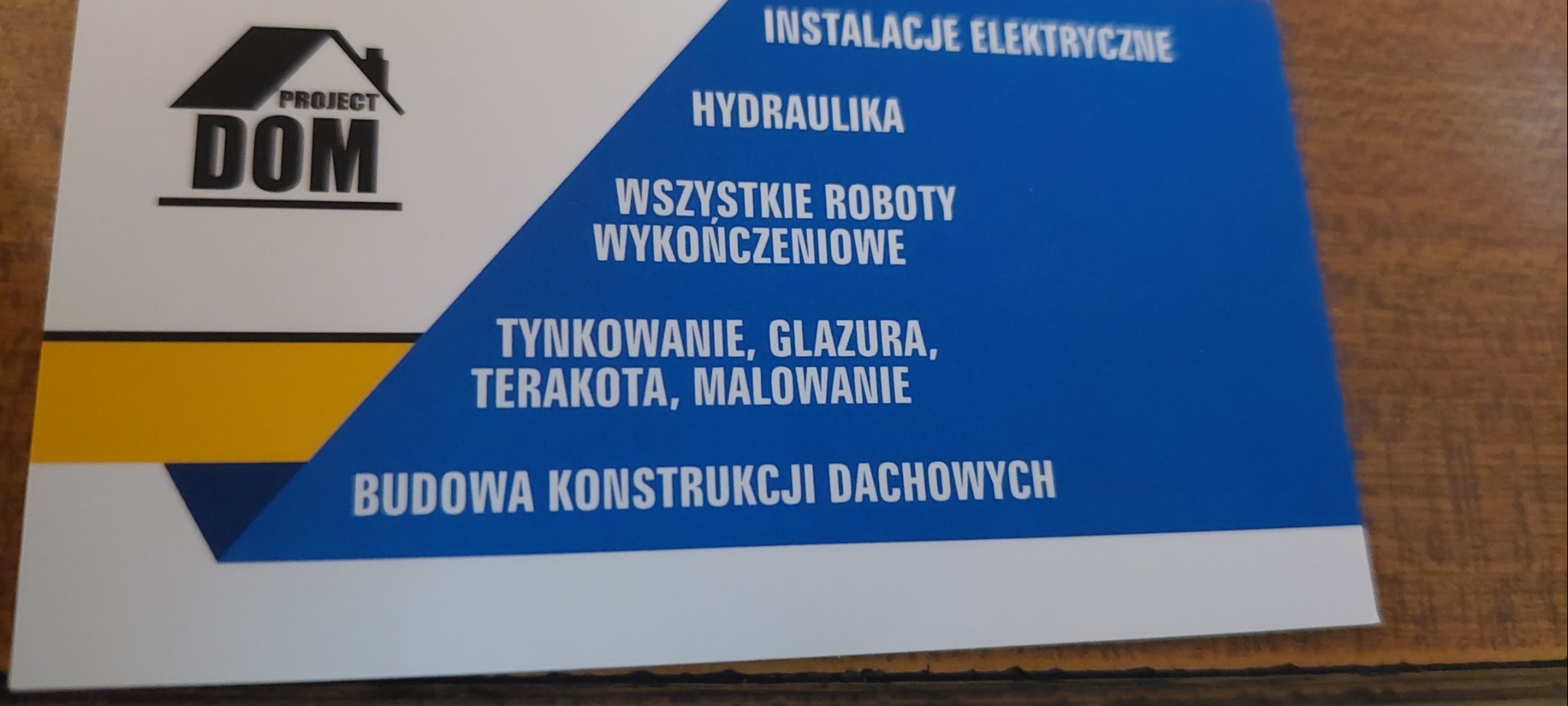 Wizytówka firmy budowlanej Project Dom, oferującej instalacje elektryczne, hydraulikę, roboty wykończeniowe, tynkowanie, glazurę, terakotę, malowanie i budowę konstrukcji dachowych.