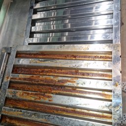 FIRMA SPSZĄTAJĄCA EFEKT RZESZOW - Dwa metalowe filtry przemysłowe, jeden czysty i błyszczący, drugi silnie zabrudzony zaschniętym tłuszczem i brudem, ukazujący kontrast przed i po czyszczeniu.