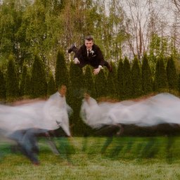 STARWAY STUDIO - MISTRZ FOTOGRAFII ŚLĄSKI - Dynamiczne ujęcie pana młodego w locie na tle zieleni, z efektem rozmycia ruchu i drzew w tle. Nietypowa fotografia ślubna w plenerze.