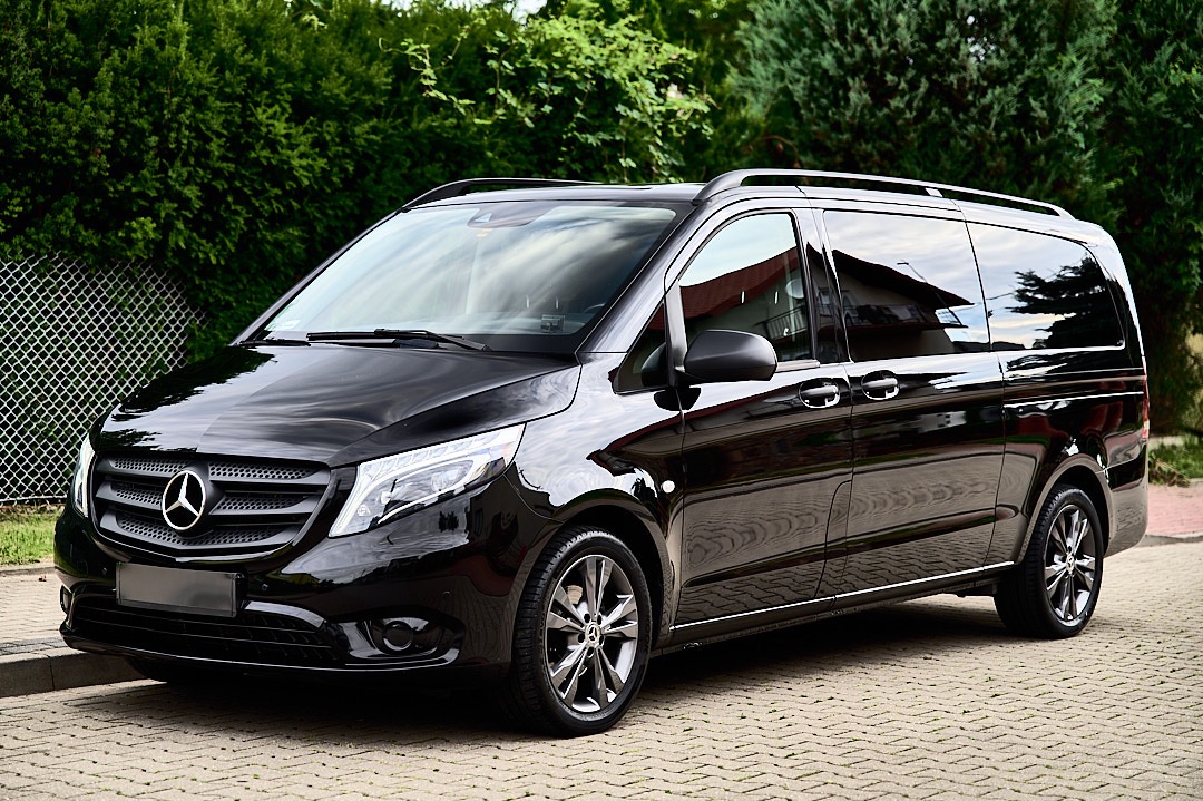 Błyszczący, czarny Mercedes-Benz Vito z relingami dachowymi, zaparkowany na brukowanej nawierzchni, z widocznym logo marki na przedniej atrapie chłodnicy.