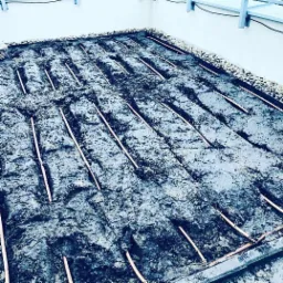 Instalacja rur nawadniających w wykopanych rowkach, przygotowanych pod trawnik na dachu budynku, obrzeża wykończone drobnym kamieniem