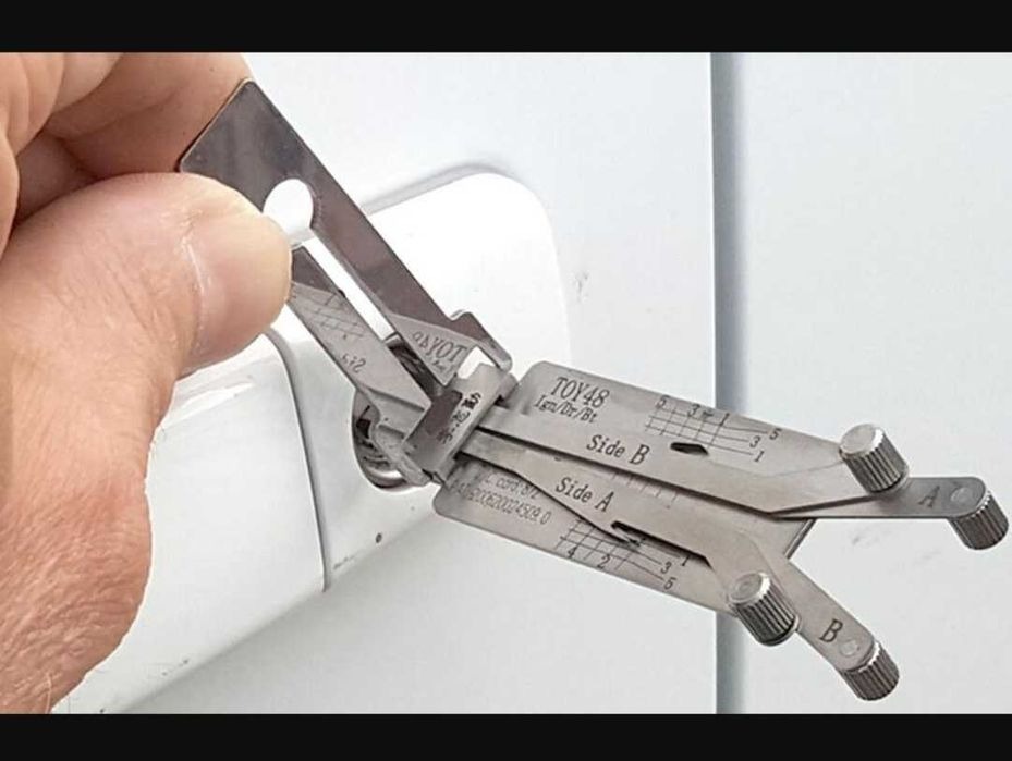 Otwieranie zamka w drzwiach za pomocą specjalistycznego narzędzia ślusarskiego TOY48, widoczne oznaczenia Side A i Side B oraz uchwyt narzędzia w dłoni.