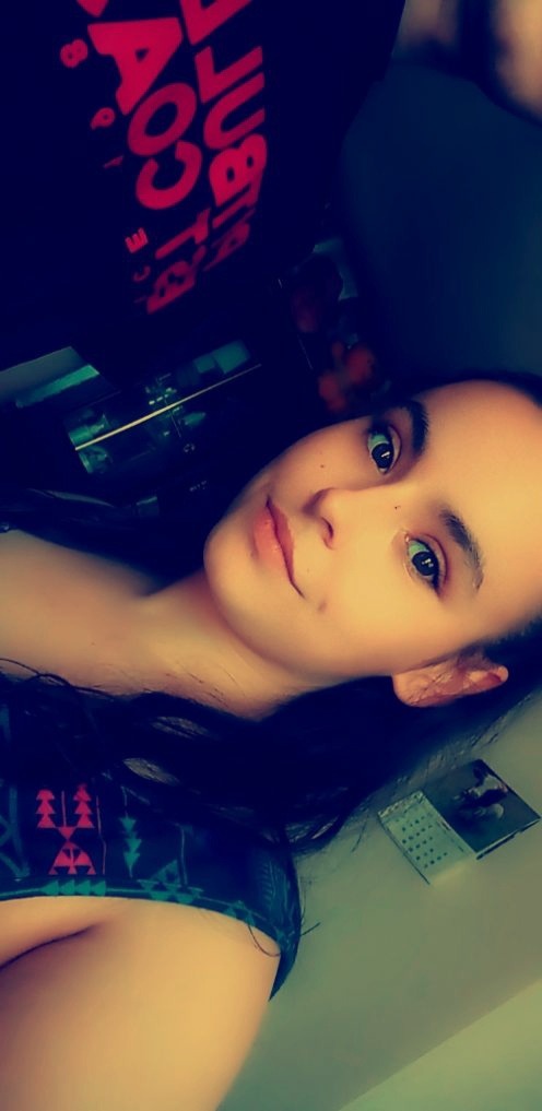 Portret kobiety z ciemnymi włosami, z kalendarzem i ramką na ścianie w tle.