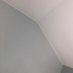 Farbeman - Ściana i sufit po malowaniu na szaro i biało, widoczne ostre krawędzie i kąty, minimalistyczne ujęcie z dołu.