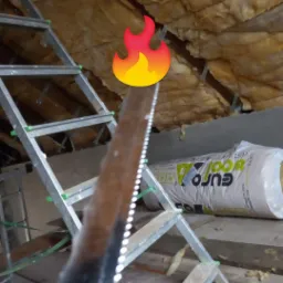 Montaż izolacji z wełny mineralnej na poddaszu, widoczna drabina, wełna w rolkach Euro-Wool i fragment dachu z izolacją.