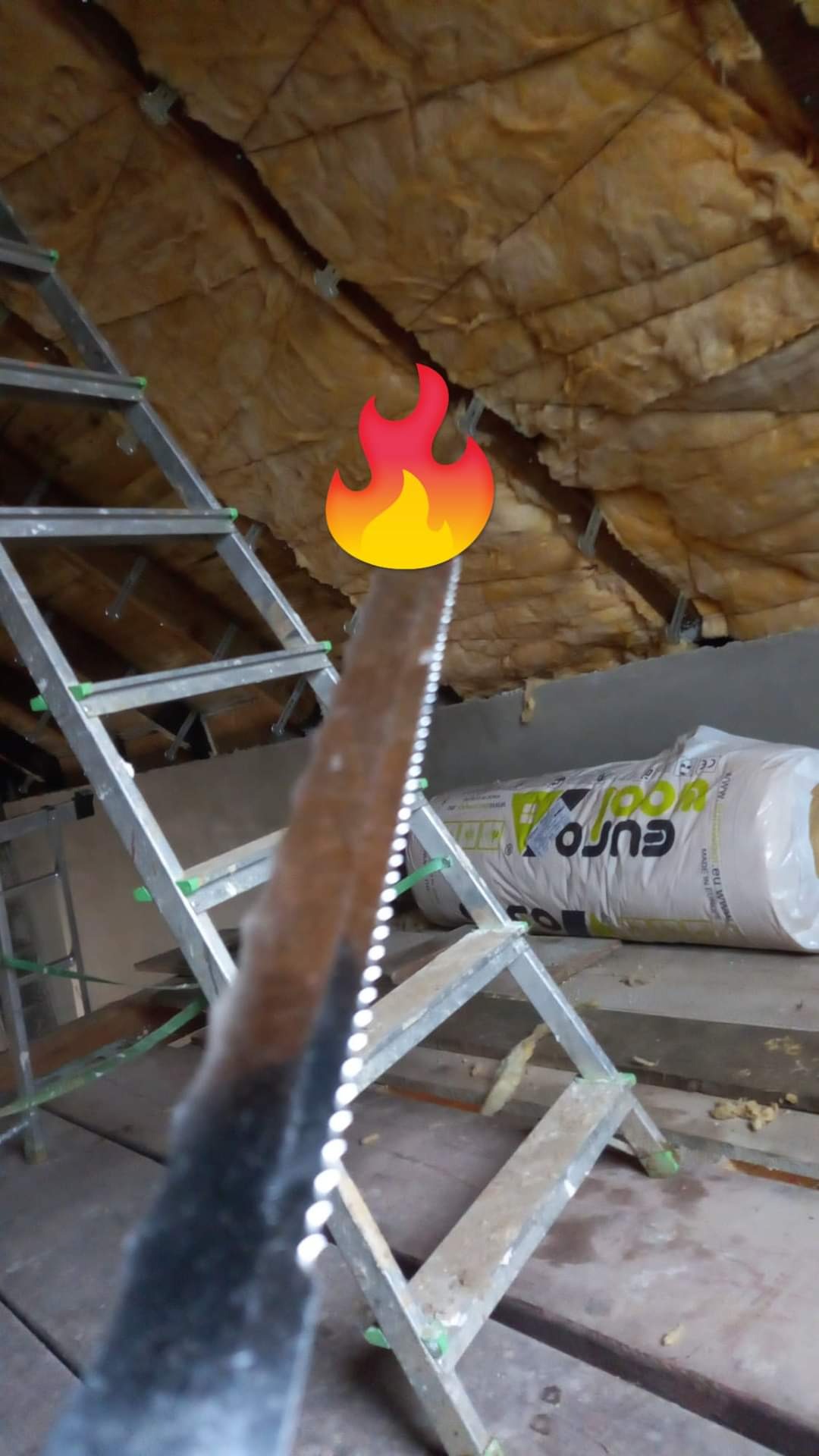 Montaż izolacji z wełny mineralnej na poddaszu, widoczna drabina, wełna w rolkach Euro-Wool i fragment dachu z izolacją.