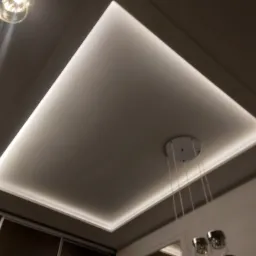 Podwieszany sufit z oświetleniem LED w kształcie prostokąta, widoczne elementy dekoracyjne i fragment lampy wiszącej.