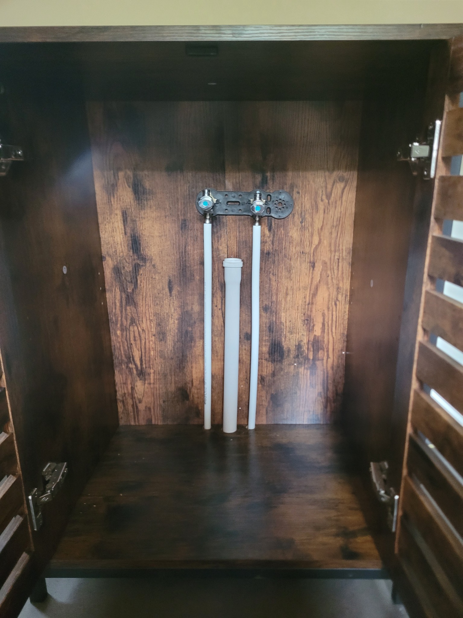 Wnętrze szafki z widocznymi rurami hydraulicznymi i zaworami, instalacja w Sanoku.