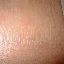 Tekstura ściany pokryta stiukiem w odcieniach brzoskwini i bieli, z widocznymi smugami i nierównościami.