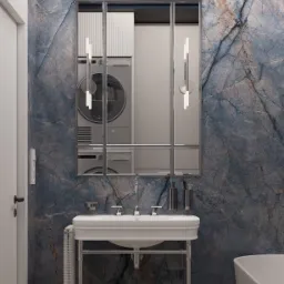 Elegancka łazienka z umywalką na metalowym stelażu, lustrem z podziałami, marmurową ścianą w odcieniach granatu i szarości oraz pralką i suszarką widoczną w odbiciu lustra.