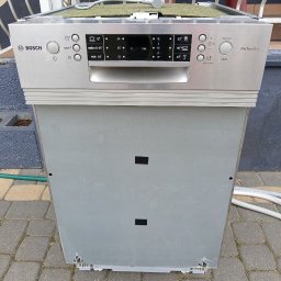 Sebastian Warchoł - Zdemontowana zmywarka Bosch PerfectDry na zewnątrz, widoczne panele sterowania i uszkodzenia obudowy. Kabel zasilający na górze urządzenia.