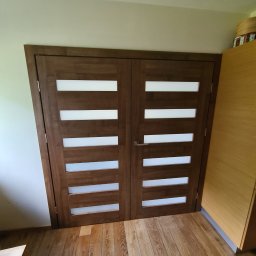 FIRMA USŁUGOWA RAFO RAFAŁ BORUTA - Dwuskrzydłowe, brązowe drzwi wewnętrzne z poziomymi, mlecznymi przeszkleniami, klamka po prawej stronie, widok z bliska na parkiet, fragment taboretu po lewej.