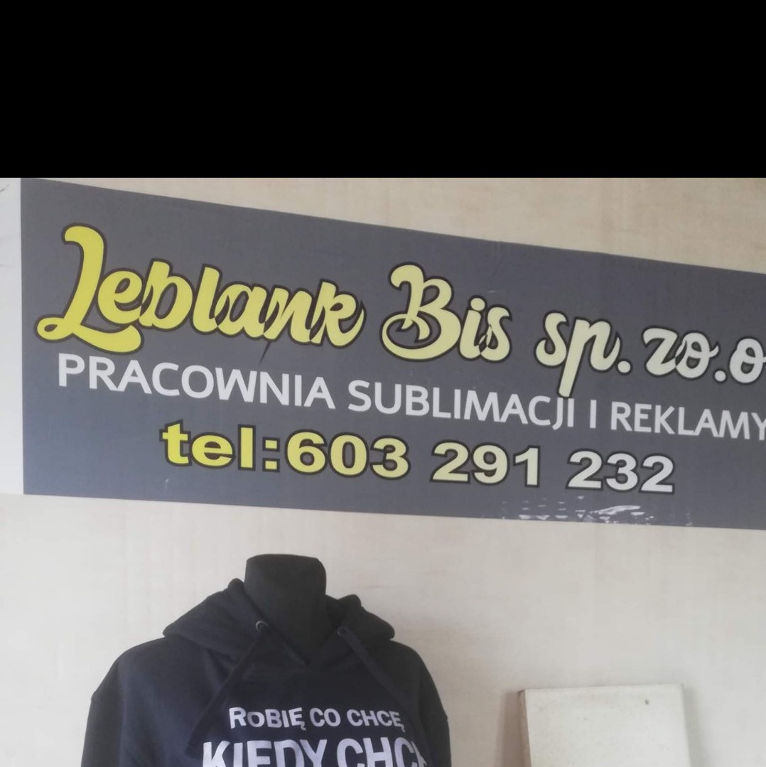 Czarna bluza z kapturem na manekinie z napisem 'Robię co chcę, kiedy chcę' na tle szyldu firmy Leblank Bis sp. z o.o. Pracownia sublimacji i reklamy z numerem telefonu.