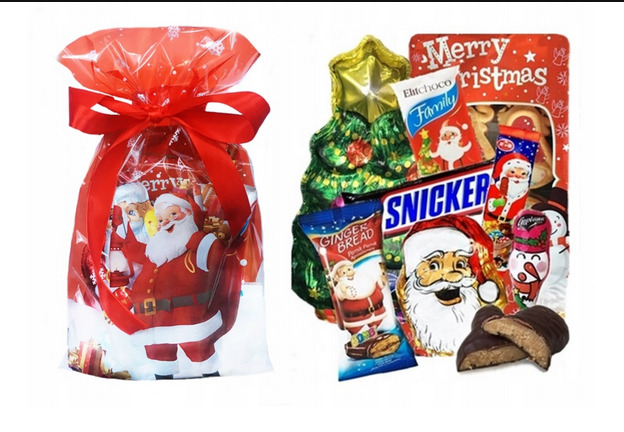Świąteczny zestaw słodyczy w celofanowym worku z motywem Świętego Mikołaja, obok czekoladowy choinka i mix słodkich przekąsek w opakowaniach z Mikołajem.