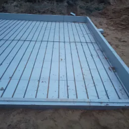 Przygotowany szalunek z izolacją termiczną i zbrojeniem stalowym, gotowy do zalania betonem pod płytę fundamentową na gruncie.