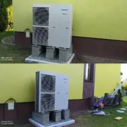 Zewnętrzna jednostka pompy ciepła Panasonic Inverter, zamontowana na betonowych podstawach z szarym żwirem, przy żółtej ścianie budynku z brązowym cokołem. Widoczne przewody i elementy instalacyjne...