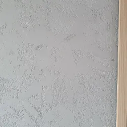 Szara ściana z dekoracyjną fakturą obok pionowych drewnianych listew.