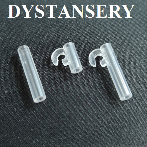 Przezroczyste, plastikowe elementy montażowe z haczykami na ciemnym tle, prawdopodobnie do mocowania sznurków lub łańcuszków regulacyjnych.