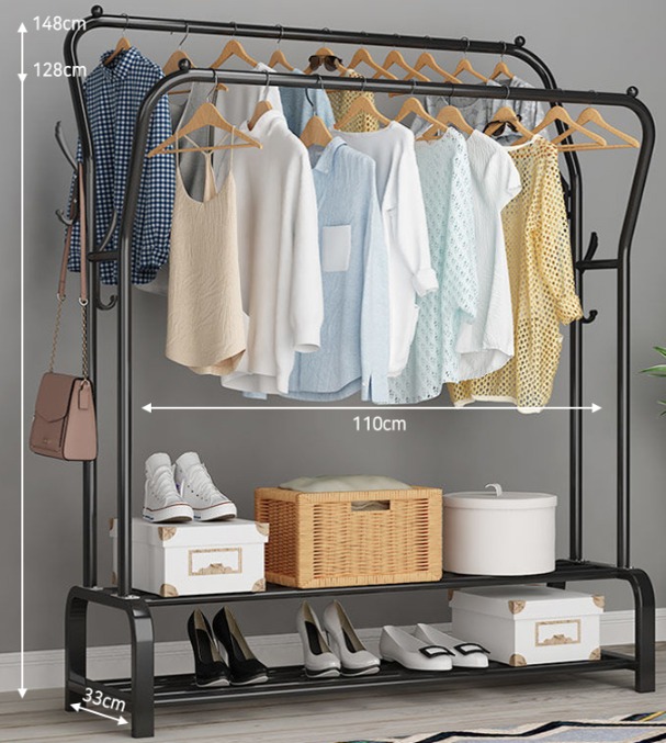 Metalowy wieszak na ubrania z dwoma poziomami, na górnym poziomie wiszą ubrania na wieszakach, na dolnym pudełka, buty i wiklinowy koszyk.