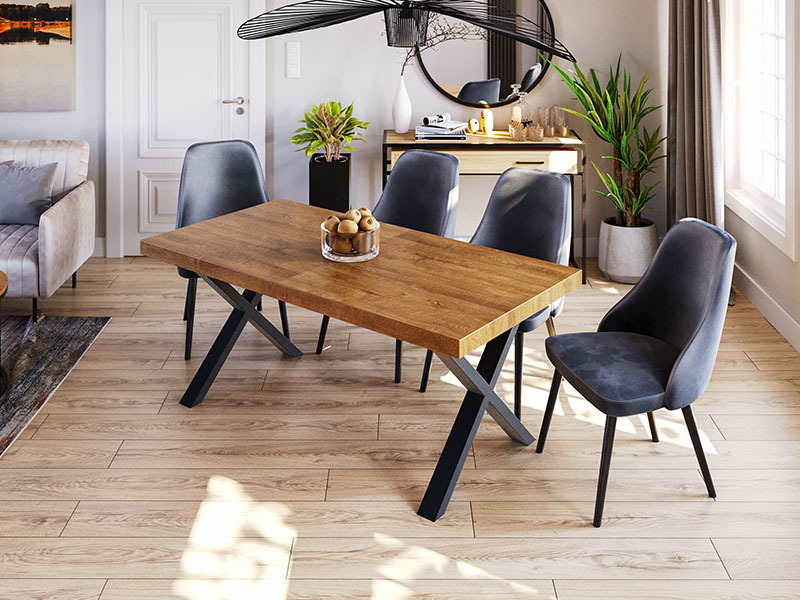 Rustykalny stół z drewnianym blatem i czarnymi, metalowymi nogami w kształcie litery X, otoczony czterema szarymi krzesłami w nowoczesnym wnętrzu z drewnianą podłogą i dekoracjami.