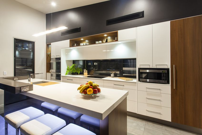 Nowoczesna kuchnia w Człuchowie z wyspą, białymi frontami szafek, drewnianymi akcentami i oświetleniem LED pod blatem wyspy.