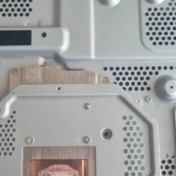 Wnętrze konsoli PS4 Pro z widocznym procesorem i pozostałościami starej pasty termoprzewodzącej na radiatorze, przygotowane do wymiany pasty.