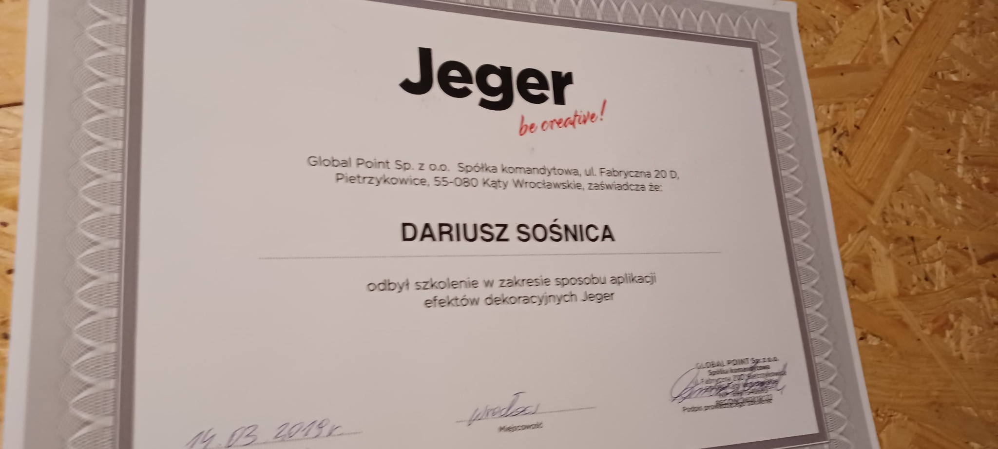 Certyfikat firmy Jeger potwierdzający odbycie szkolenia z zakresu aplikacji efektów dekoracyjnych, z widocznym imieniem i nazwiskiem Dariusza Sośnicy oraz datą 14.03.2019, umieszczony na tle płyty...