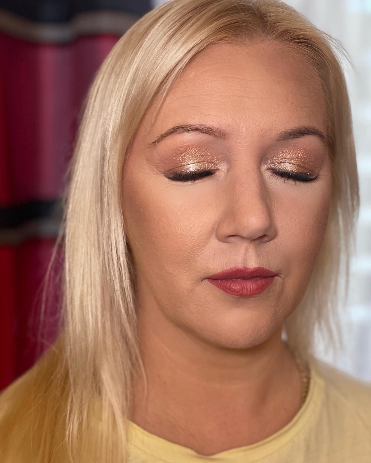 Portret kobiety z zamkniętymi oczami prezentującej złoty, błyszczący cień do powiek i matową pomadkę w odcieniu dusty rose.