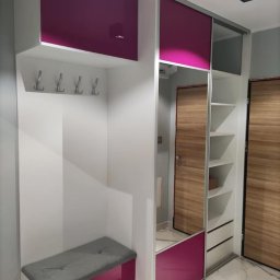 AgaMeble - Wnęka z szafą przesuwną, siedziskiem i wieszakami, wykończona w bieli i fuksji, z lustrzanym frontem i drewnianymi drzwiami w tle.