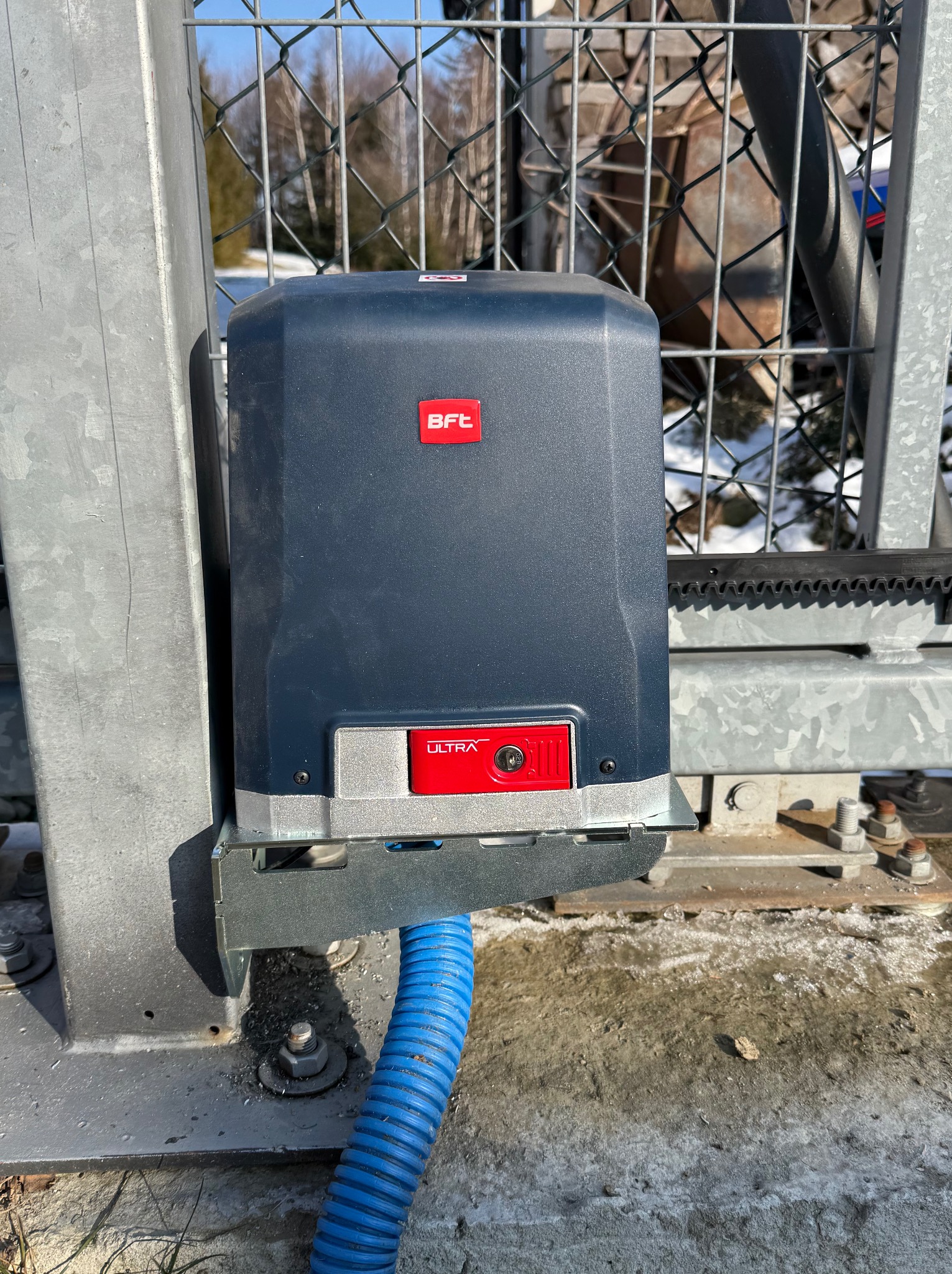 Zamontowany napęd BFT Ultra na bramie posesji w Chełmcu. Widoczna listwa zębata i niebieski peszel. Fragment zimy w tle.