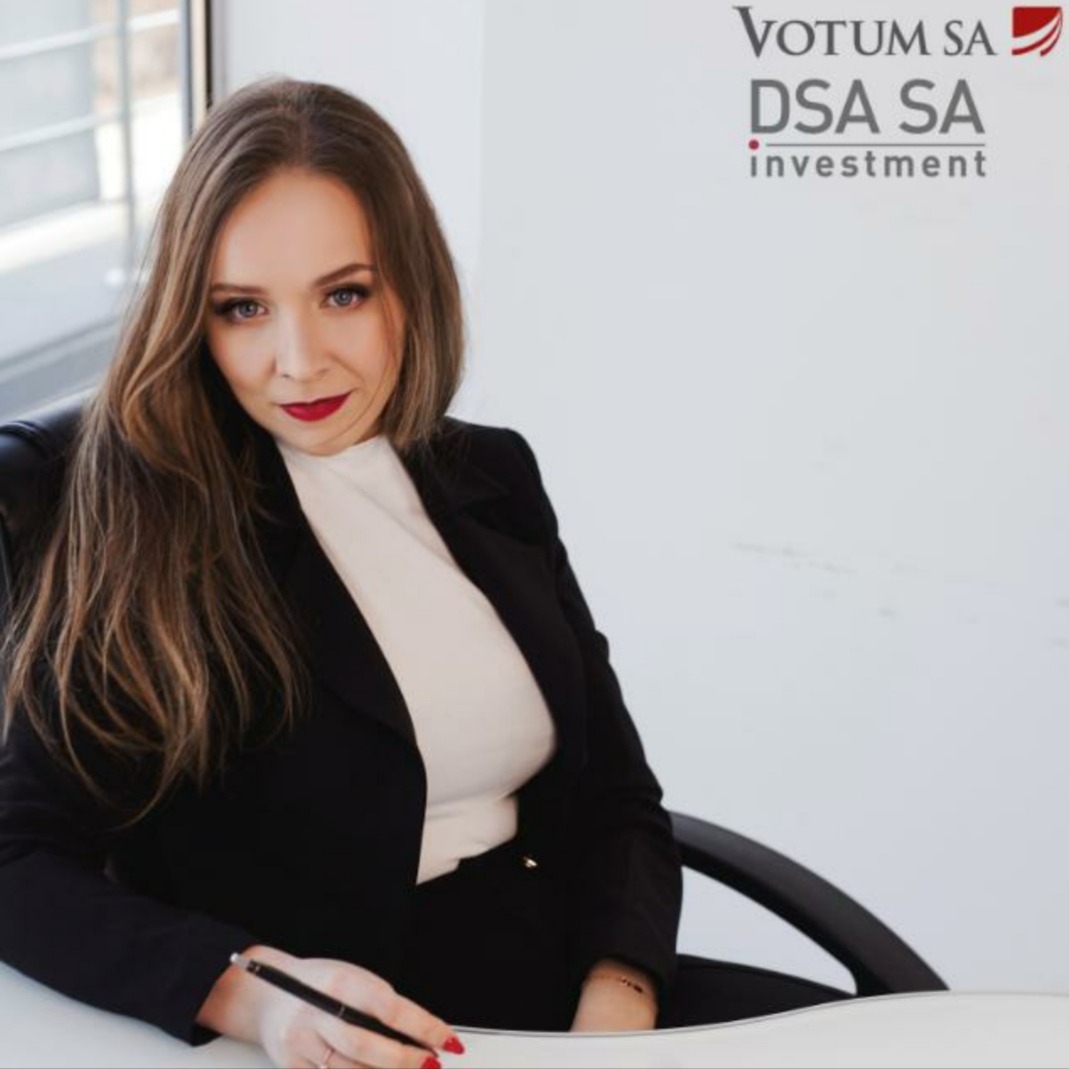 Kobieta w czarnym żakiecie siedzi przy biurku i pisze, w tle logo firmy Votum DSA SA investment.