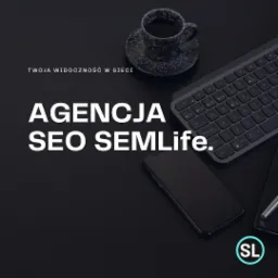 Biurko z czarnym tłem, na którym leżą: filiżanka kawy w czarno-białe plamki, klawiatura, smartfon, notatnik z długopisem oraz logo Agencji SEO SemLife. Widoczny napis: Twoja widoczność w sieci.