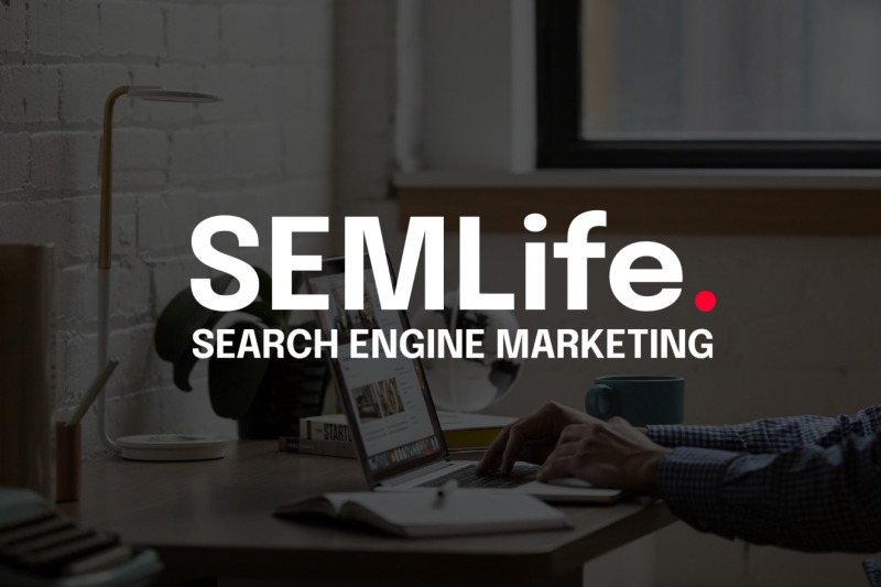 SEMlife logo superimposed over a desk scene with hands typing on a laptop, a lamp, a mug and a notebook.