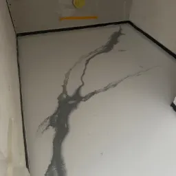 Jasnoszara posadzka żywiczna z ciemnoszarym wzorem przypominającym marmur w nowym pomieszczeniu z surowymi ścianami i widocznymi instalacjami