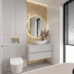 Nowoczesna łazienka z okrągłym lustrem podświetlanym LED, białą umywalką nablatową i grzejnikiem drabinkowym w kolorze czarnym.