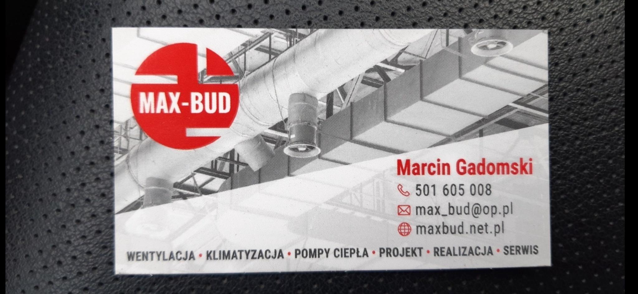 Wizytówka firmy Max-Bud z czerwonym logo na tle czarno-białego zdjęcia instalacji wentylacyjnej, prezentująca dane kontaktowe Marcin Gadomski, numer telefonu, adres e-mail i stronę internetową,...