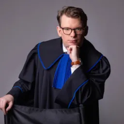 Portret mężczyzny w todze adwokackiej, z ręką pod brodą, na szarym tle.