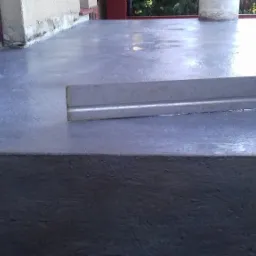 Wyrównywanie wylewki na betonowym tarasie przed wejściem do domu, widoczna poziomica i świeżo wylana, mokra powierzchnia.