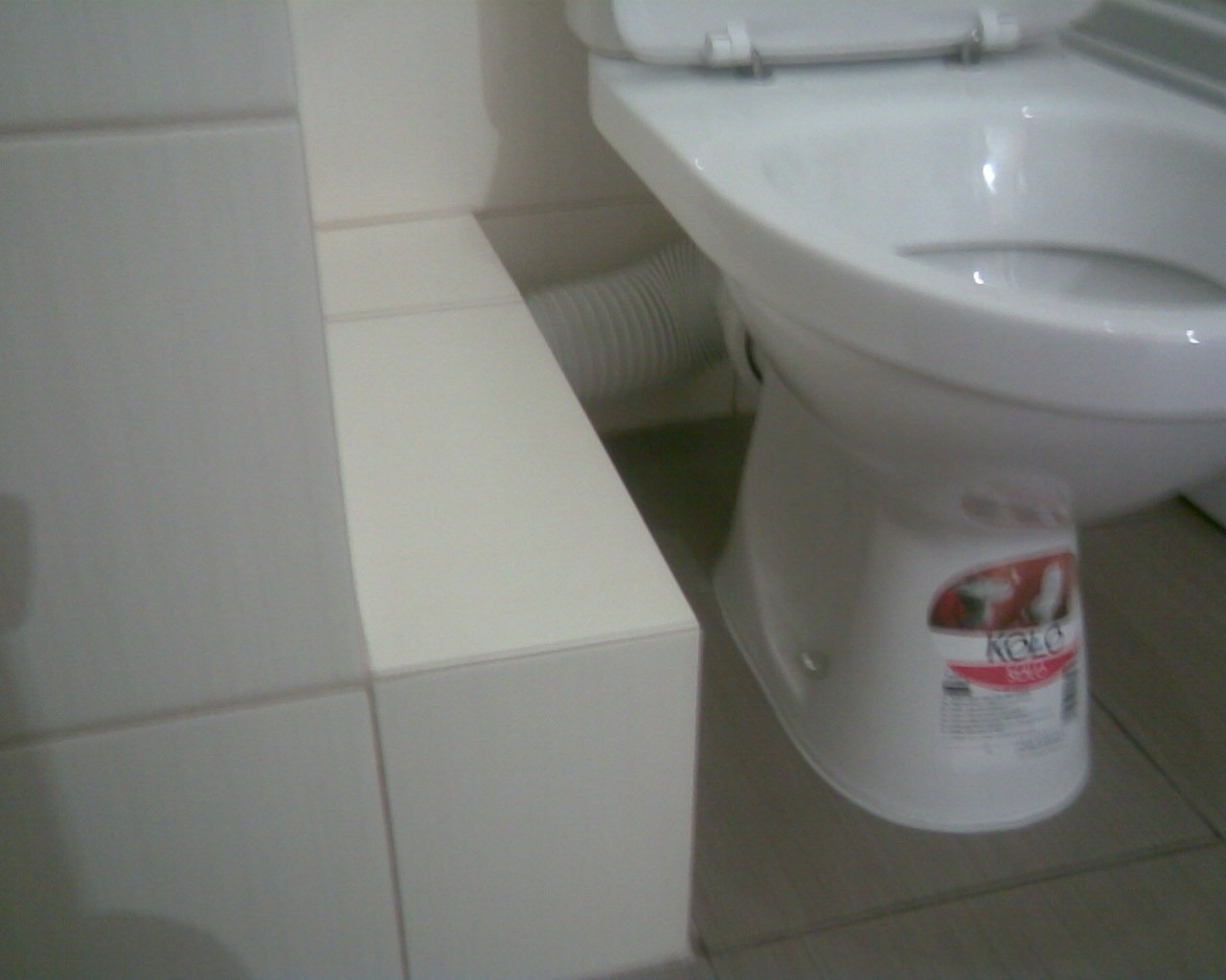 Biała toaleta marki Koło z widoczną etykietą, zamontowana w łazience w Płocku, obok zabudowa z płytek.