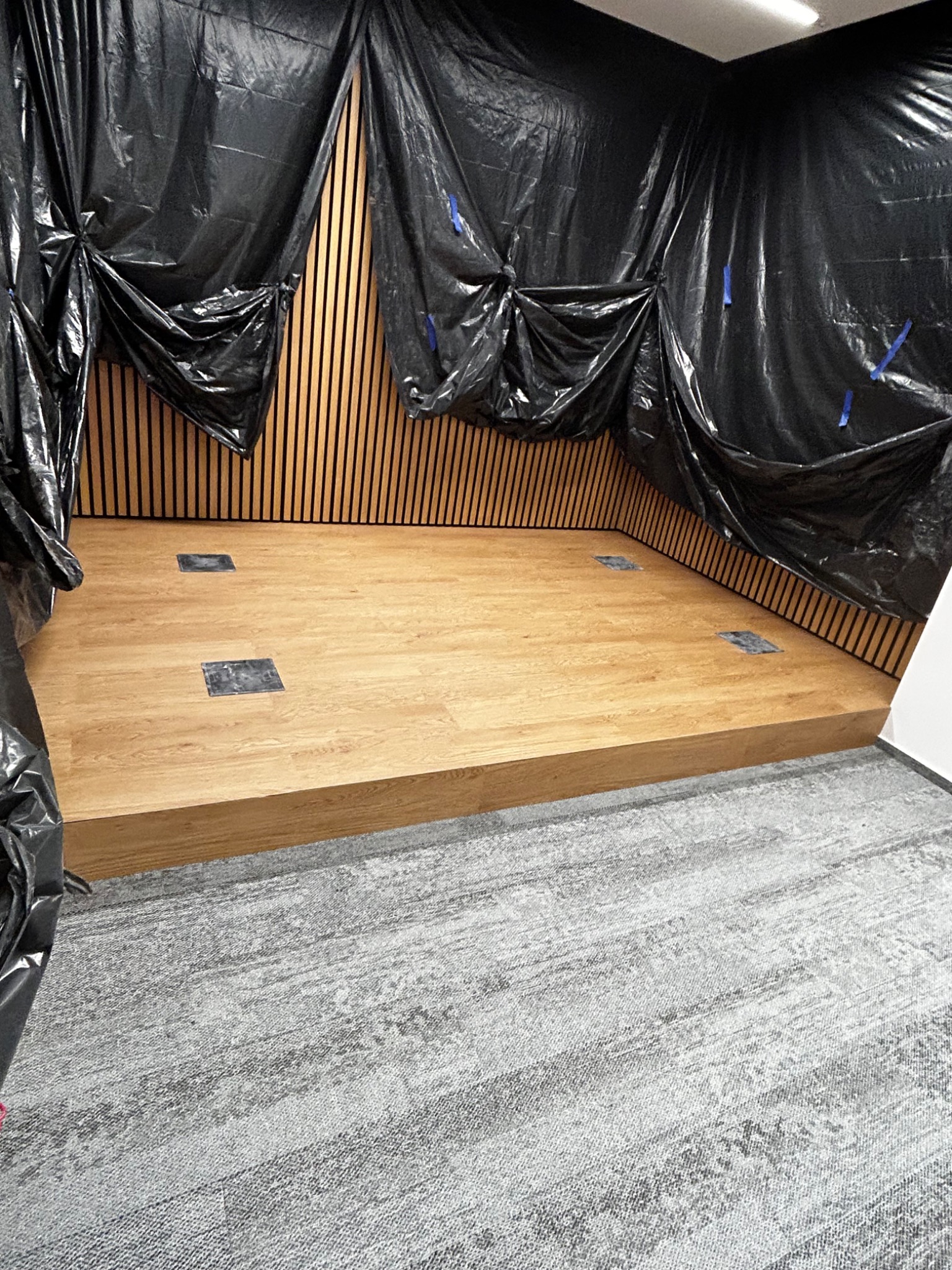 Nowa podłoga z paneli, zabezpieczona folią malarską na ścianach, z widocznymi puszkami podłogowymi.