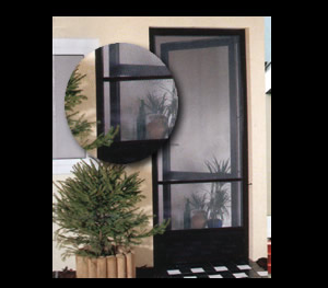 Czarna moskitiera ramkowa zamontowana w drzwiach balkonowych, widoczna roślina doniczkowa przed drzwiami, fragment okna z moskitierą w tle.