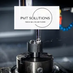 Frezarka CNC w trakcie obróbki metalu, widoczne chłodziwo i logo firmy PMT Solutions nałożone na zdjęcie.