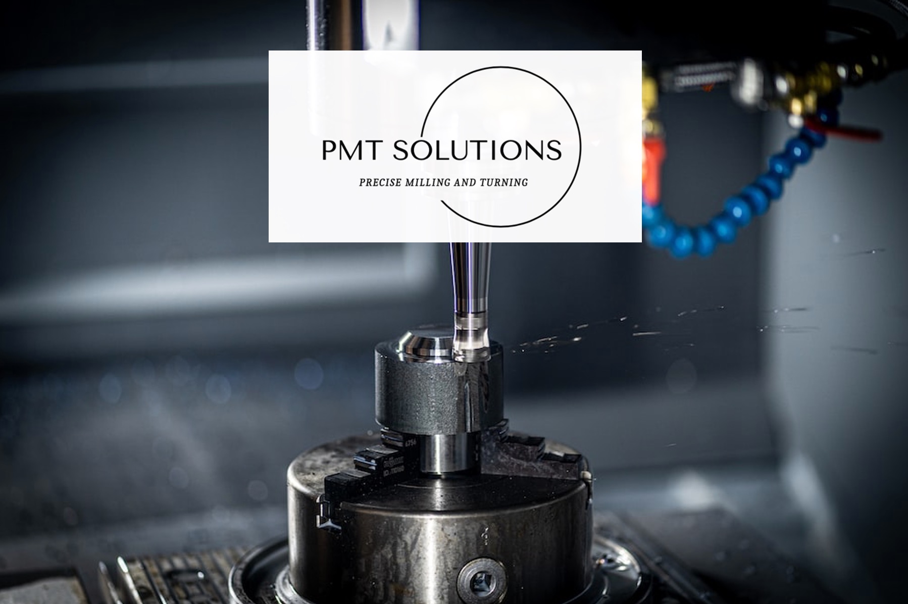 Frezarka CNC w trakcie obróbki metalu, widoczne chłodziwo i logo firmy PMT Solutions nałożone na zdjęcie.