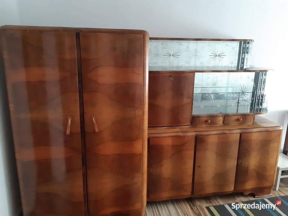 Komplet mebli w stylu art deco: wysoka szafa dwudrzwiowa i kredens z przeszkloną nadstawką w gwiazdy, wykończone fornirem o bogatym usłojeniu.