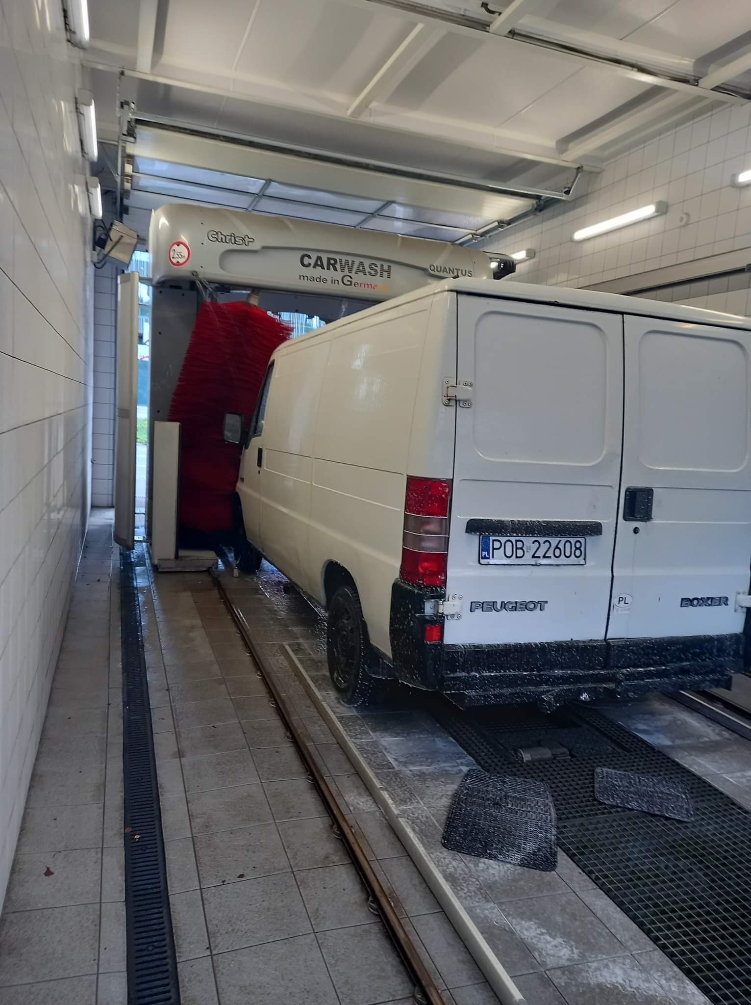 Biały bus Peugeot Boxer w automatycznej myjni samochodowej z czerwonymi szczotkami, widoczny numer rejestracyjny POB 22608.