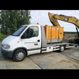 Marcel Kozłowski - Biała laweta z napisem 'AUTOHOLOWANIE' przewozi pomarańczowe agregaty prądotwórcze marki RIAL, z tyłu widoczna koparka CAT na platformie.