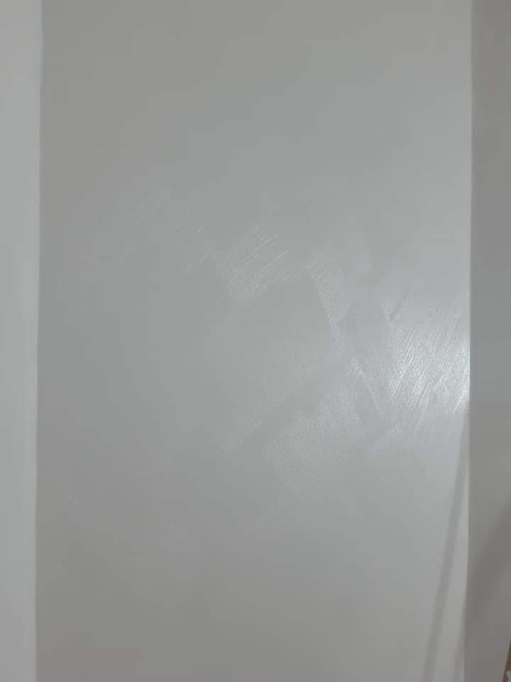 Świeżo pomalowana ściana w odcieniu chłodnej szarości, widoczne delikatne smugi po wałku, gładka powierzchnia z subtelnym połyskiem.