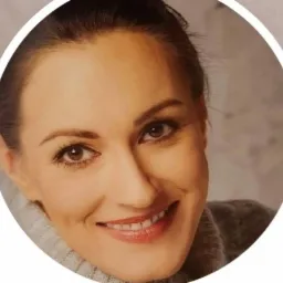 Portret uśmiechniętej brunetki w szarym swetrze, z delikatnym makijażem i widocznymi zmarszczkami mimicznymi wokół oczu, umieszczony w białym okręgu.