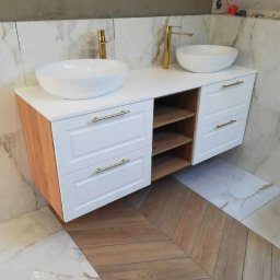 STOLARSTWO PIOTR GŁĄBOWSKI - Nowoczesna szafka łazienkowa z dwoma białymi umywalkami nablatowymi i złotą armaturą, białe fronty szuflad z frezowaniem i złotymi uchwytami, drewniane półki, marmurowe płytki ścienne i podłoga...